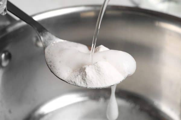 water pouring onto spoon of baking soda